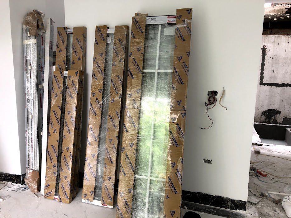 Cửa nhôm kính Xingfa mới bọc carton dựng trong nhà đang thi công xây dựng